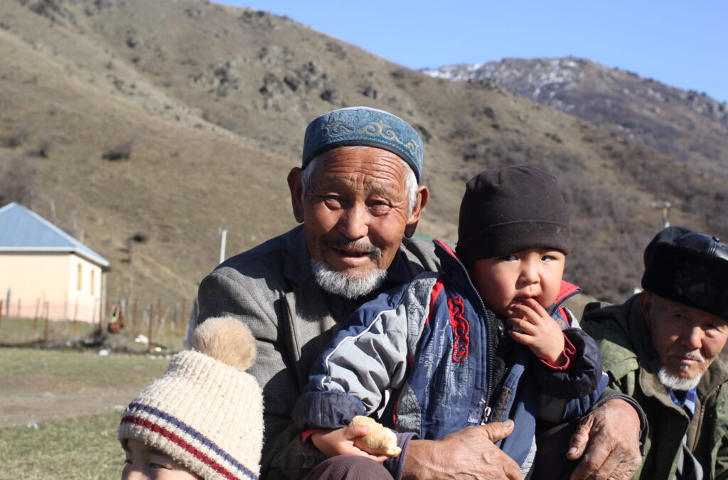 An old man holding a small child in the mountains of Kyrgizstan